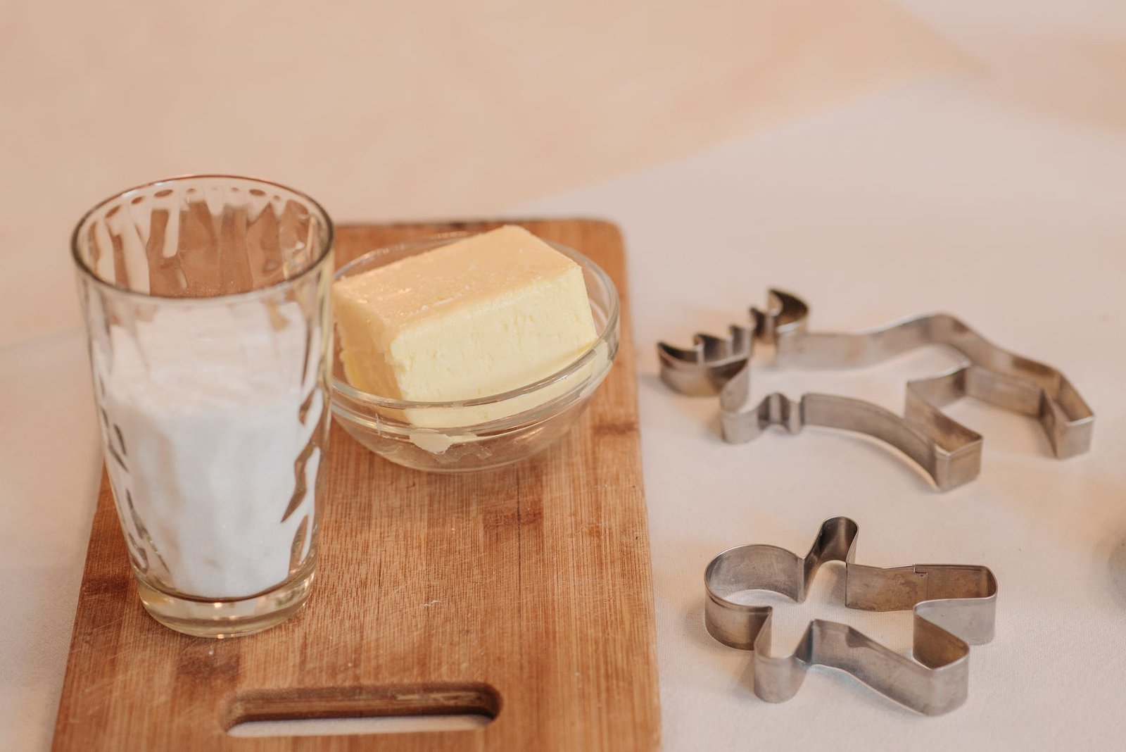 a glass of milk beside a butter in a bowl on a wooden board